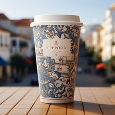 a cup of coffee sitting on top of a wooden table next to a building in the background