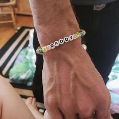 a close up of a person holding the hand of a child wearing a beaded bracelet