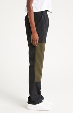 Front-zip cuffs lend styling versatility to lightweight track pants with deep front pockets and a signature logo at the calf. 31" inseam; 18" leg opening; 13 1/2" front rise; 16" back rise (size Medium) Drawcord-toggle waist Front slant pockets 100% nylon Machine wash, tumble dry Imported Nordstrom x Nike: A curated lifestyle destination where fashion is the ultimate sport Black Tapered Leg Bottoms With Zip Fly, Nike Cargo Bottoms, Black Nylon Cargo Pants For Work, Sporty Black Cargo Pants For Work, Sporty Black Pants With Zip Fly, Black Nylon Parachute Pants For Work, Black Nylon Pants With Hip Pockets, Black Nylon Bottoms For Work, Nike Nylon Bottoms With Side Pockets