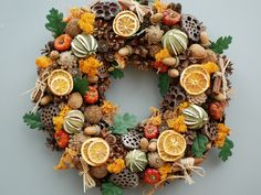 a wreath made out of dried fruit and other things is hanging on a beige wall