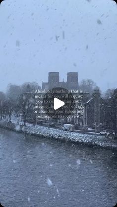 a river with snow falling on it and a building in the background that says,