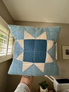 a person holding up a blue and white pillow