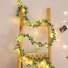 a wooden ladder decorated with greenery and lights on the wall next to a bed