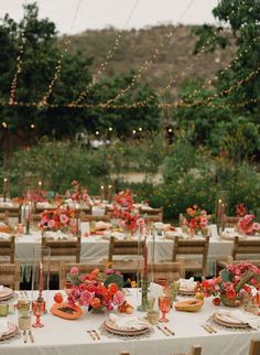 an outdoor dining area with tables and chairs covered in white linens, decorated with red flowers