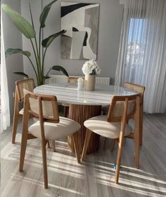 a dining room table with four chairs and a painting on the wall in the background