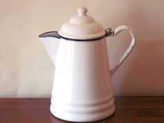 a white coffee pot sitting on top of a wooden table