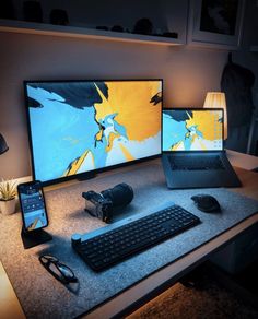 two computer monitors sitting on top of a desk next to a keyboard and mouse with a cell phone