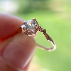 a close up of a person's hand holding a ring with a diamond in it