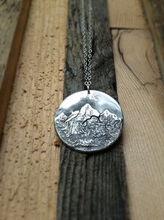 "Each pendant is hand crafted from substantial pieces of sterling silver. The texture is unique in each and every necklace. It will look a lot like the image above, but not exactly. This piece was inspired by mountain biking in California in the Sierra Nevada Mountain Range. Absolutely beautiful! If you're interested in your necklace having a particular Mountain Range, let me know! They're all made custom. The pendant dangles from a durable lovely rolo chain and lobster claw closure and can be m White Gold Etched Round Pendant Necklace, Etched White Gold Round Pendant Necklace, Unique Round White Gold Necklaces, White Gold Sterling Silver Necklace With Large Pendant, Artisan Sterling Silver Necklaces With Oxidized Finish, Artisan Sterling Silver Necklace With Oxidized Finish, Custom White Gold Sterling Silver Pendant Necklace, Etched Sterling Silver Round Necklace, Custom Sterling Silver Pendant Necklace In White Gold