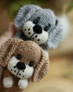 two small stuffed animals are in the palm of someone's hand, one is wearing a knitted hat