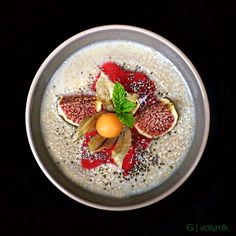 a bowl filled with oatmeal topped with fruit and garnished with mint