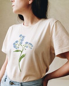 Celebrate someone special whom you missed in this Forget-me-not flower t-shirt. Original botanical design you won't find anywhere else. Printed on a Cream cotton tshirt - soft to the touch and lightweight. Unisex fit - boxy and long. Prints are original watercolor designs hand-painted by a botanical artist. How it's made: * Ethically made 100% cotton t-shirts that are made to last. * T-shirts are printed and shipped by my printing partner in the US, Canada, or Europe. * By buying from this shop you are directly supporting a woman-owned small business, created out of love for plants to educate, inspire and keep us connected to the natural world. About the artist: This Shop is an extension of my botanical illustration studio, where I create hand-painted watercolor art for international clien June Birth Flower, Floral Clothing, Watercolor Designs, Illustration Botanique, Botanical Shirt, Botanical Poster, Floral Outfit, Birth Month Flowers, Flower Tops