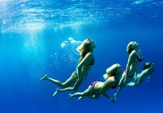 three women in bikinis swimming under water