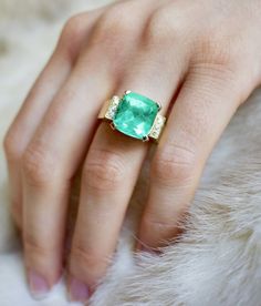 a woman's hand with an emerald and diamond ring