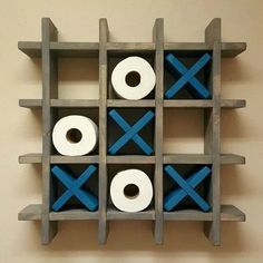 two rolls of toilet paper sitting on top of a wooden shelf with blue crosses painted on it