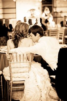 a bride and groom kissing while sitting in a chair