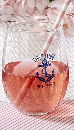 a glass filled with liquid sitting on top of a table next to some pink flowers