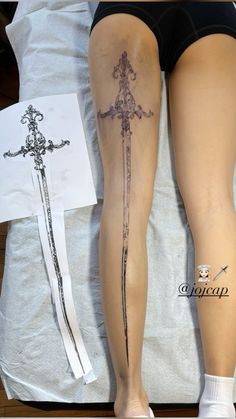 a woman's legs with tattoos on them and two swords in front of her