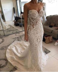 a woman standing in front of a mirror wearing a wedding dress