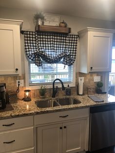 a kitchen with white cabinets and black checkered window valance over the sink area