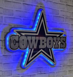 a neon sign that says cowboys on the side of a brick wall with a star