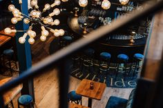 an overhead view of a bar with blue chairs and wooden tables in the foreground