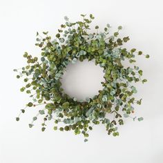 a wreath made out of green leaves on a white wall