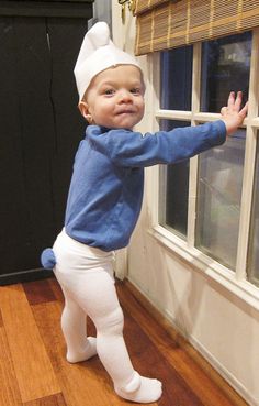 a little boy dressed up in a chef's hat and leggings standing by a window