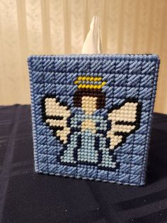 a blue and white beaded square with an angel design on it's side