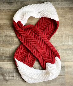 a red and white knitted scarf sitting on top of a wooden floor