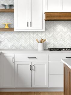 a kitchen with white cabinets and wood flooring is pictured in this image, there are wooden shelves above the stove