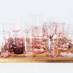 many different colored glasses are lined up on a wooden tray