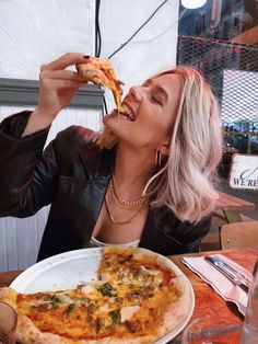 a woman sitting at a table eating pizza