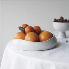 a white bowl filled with oranges on top of a table