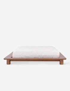 the bed frame is made from wood and has a white sheet on top of it