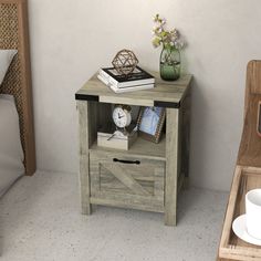 a bedside table with a clock and some books on it next to a bed in a room