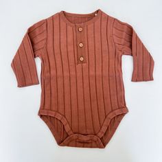 Play Up is a sustainable clothing brand with entirely Portuguese artisan design and manufacturing. They are committed to environmental preservation through their use of natural dyes, recycled fibers, and organic cotton. Long sleeve brick onesie made from organic cotton and Standard 100 by Oeko-Tex Certified non-toxic. Cotton Ribbed Solid Color Bodysuit, Cotton Ribbed Solid Bodysuit, Cotton Ribbed Onesie In Solid Color, Solid Color Cotton Ribbed Onesie, Casual Ribbed Onesie For Loungewear, Ribbed Cotton Onesie, Casual Ribbed Onesie, Casual Brown Bodysuit, Casual Brown Long Sleeve Bodysuit