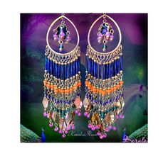 a pair of earrings with beads and chains hanging from it's ear ends on a purple background