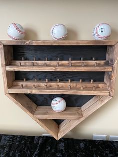 three baseballs are sitting on top of a wooden shelf with two balls in it