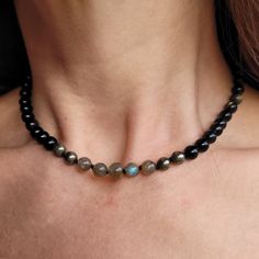 "Refine your style with this exquisite choker necklace, handcrafted with a striking combination of beaded gold obsidian, pyrite, and labradorite on black knotted silk.  Each bead is carefully selected for its natural variations, lending the piece a unique and nuanced identity. The black knotted silk provides a sophisticated backdrop for the shimmering beads, while the choker style adds a bold and contemporary touch to any outfit. Whether you're dressing up for a special occasion or elevating you Adjustable Labradorite Gemstone Beaded Necklaces, Labradorite Beaded Round Necklaces, Adjustable Labradorite Necklaces With Round Beads, Labradorite Beaded Jewelry As A Gift, Elegant Choker With Natural Stones And Round Beads, Obsidian Beaded Jewelry For Healing, Round Hematite Gemstone Beads Jewelry, Elegant Choker With Round Natural Stones, Gift Labradorite Jewelry With Polished Beads