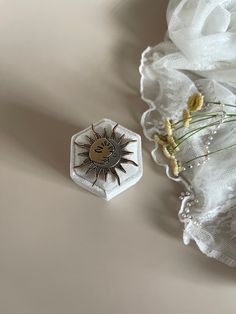 a white flower and a small brooch sitting on top of a piece of cloth