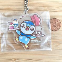 a plastic keychain with a cartoon penguin holding a cupcake on it's side