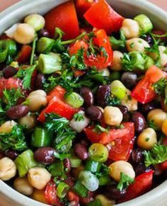 a white bowl filled with black beans, tomatoes and other vegetables on top of a wooden table