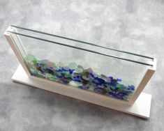 a glass display case filled with lots of blue and green rocks on a white stand