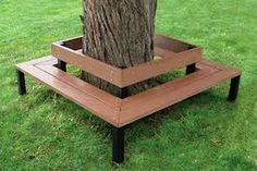 a wooden bench next to a tree in the grass