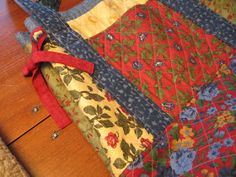 an old quilt is laying on top of a wooden table with a red ribbon tied to it