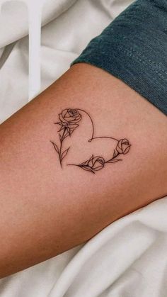 a woman's thigh with a rose and heart tattoo on her left side ribcage