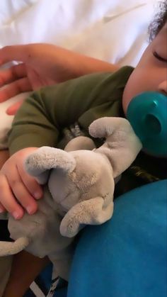 a baby sleeping with a pacifier in it's mouth while holding a stuffed animal