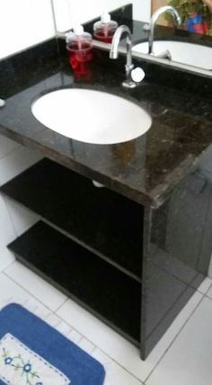 a bathroom with a sink, mirror and towel on the floor in front of it