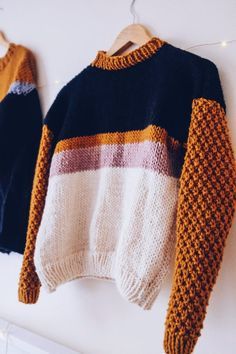 two sweaters hanging up on a wall